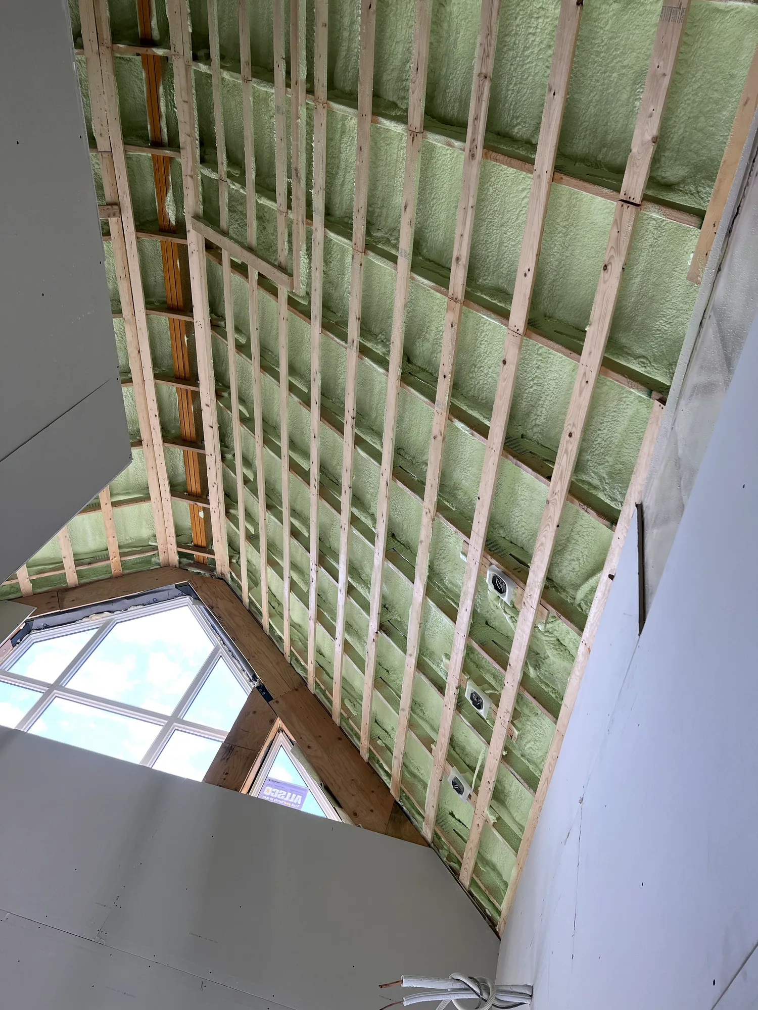 Insulated rafter bays in a vaulted ceiling with a skylight, prepared for drywall installation